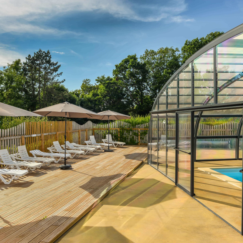 Piscine couverte et terrasse avec chaises longues.