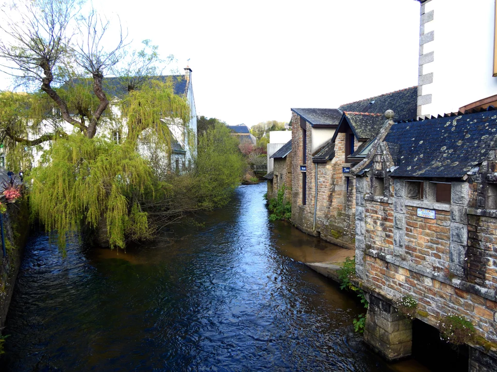 Rivière bordée de maisons et arbres.