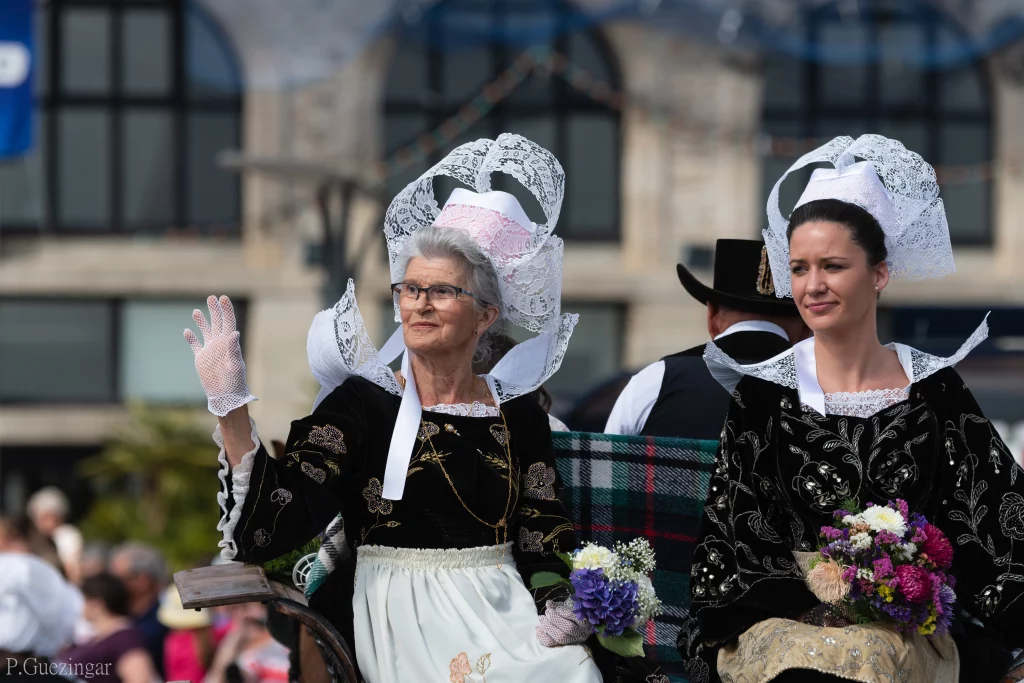 Vrouwen in traditionele Bretonse klederdracht met boeketten bloemen.