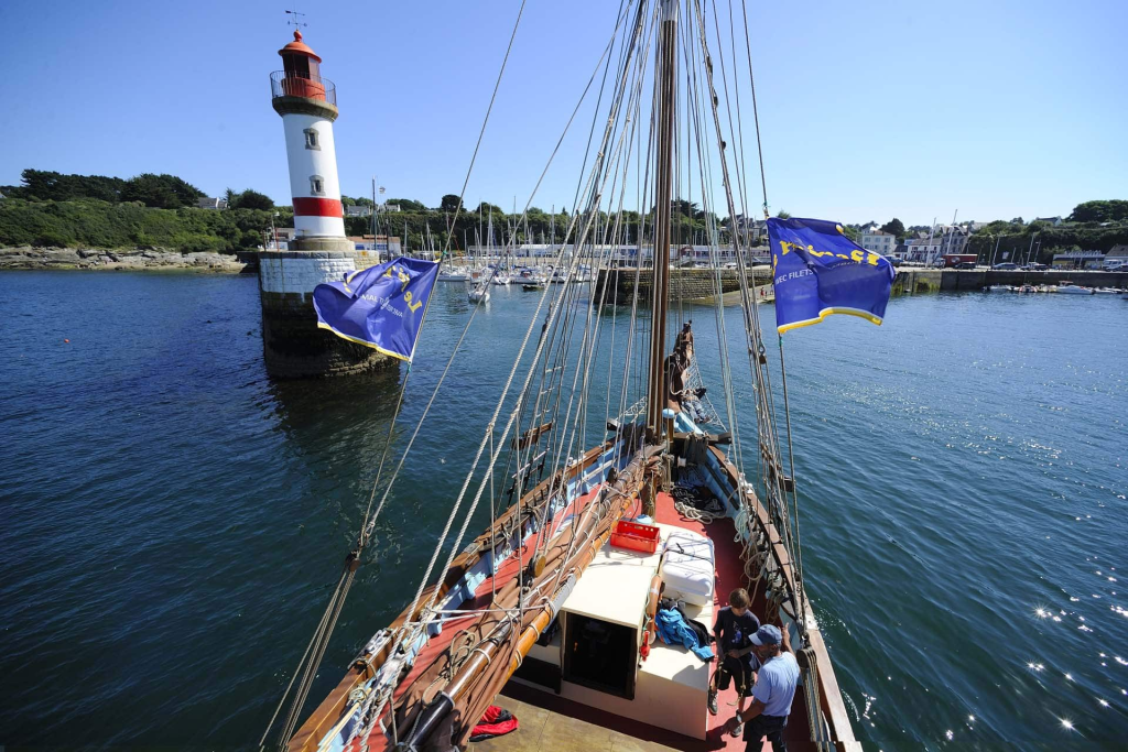 Phare et bateau dans un port français ensoleillé.