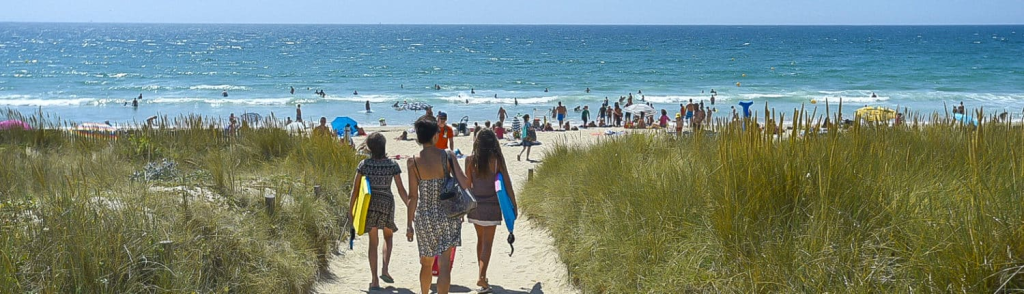 Plage bondée avec vacanciers et parasols colorés.