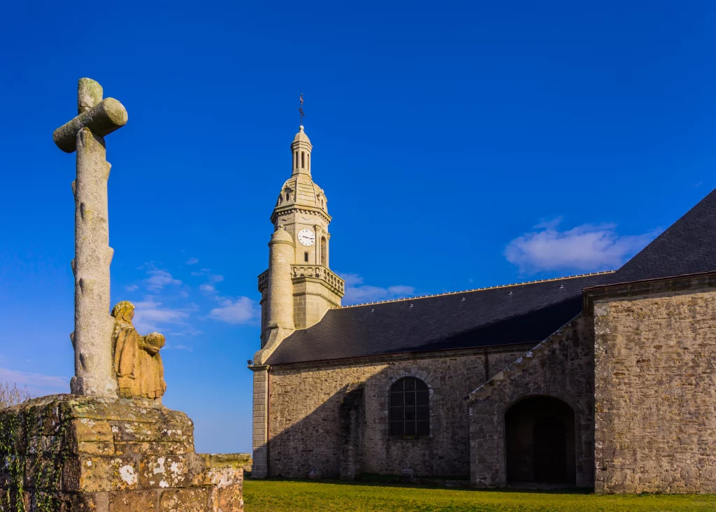 Steinkirche mit Glockenturm und geschnitztem Kreuz