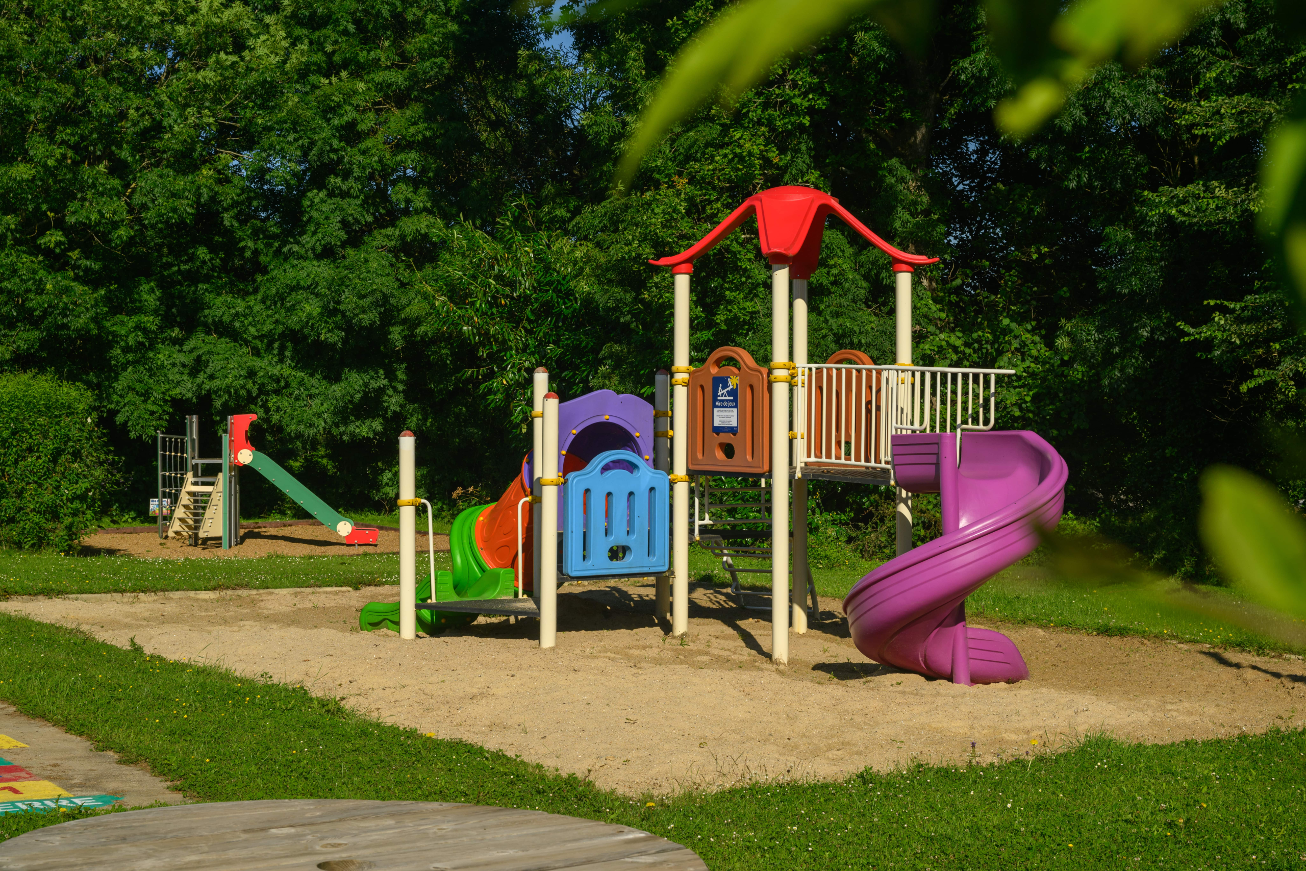 Aire de jeux colorée dans un parc verdoyant.