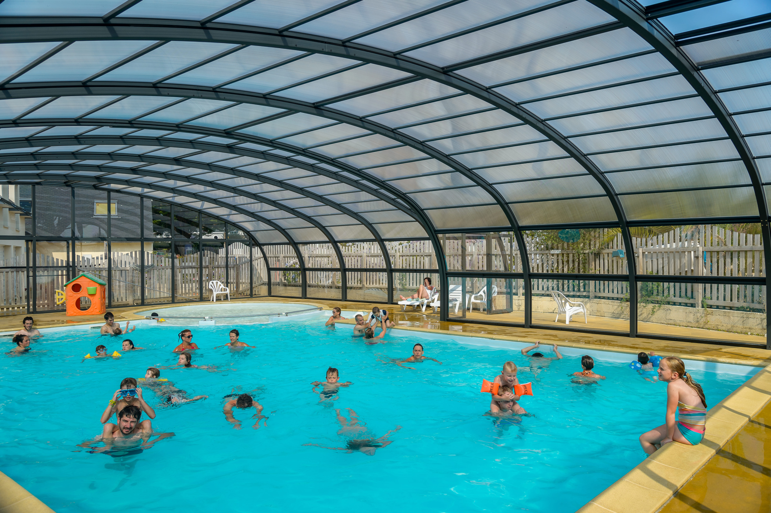 Piscine couverte avec enfants nageant joyeusement.