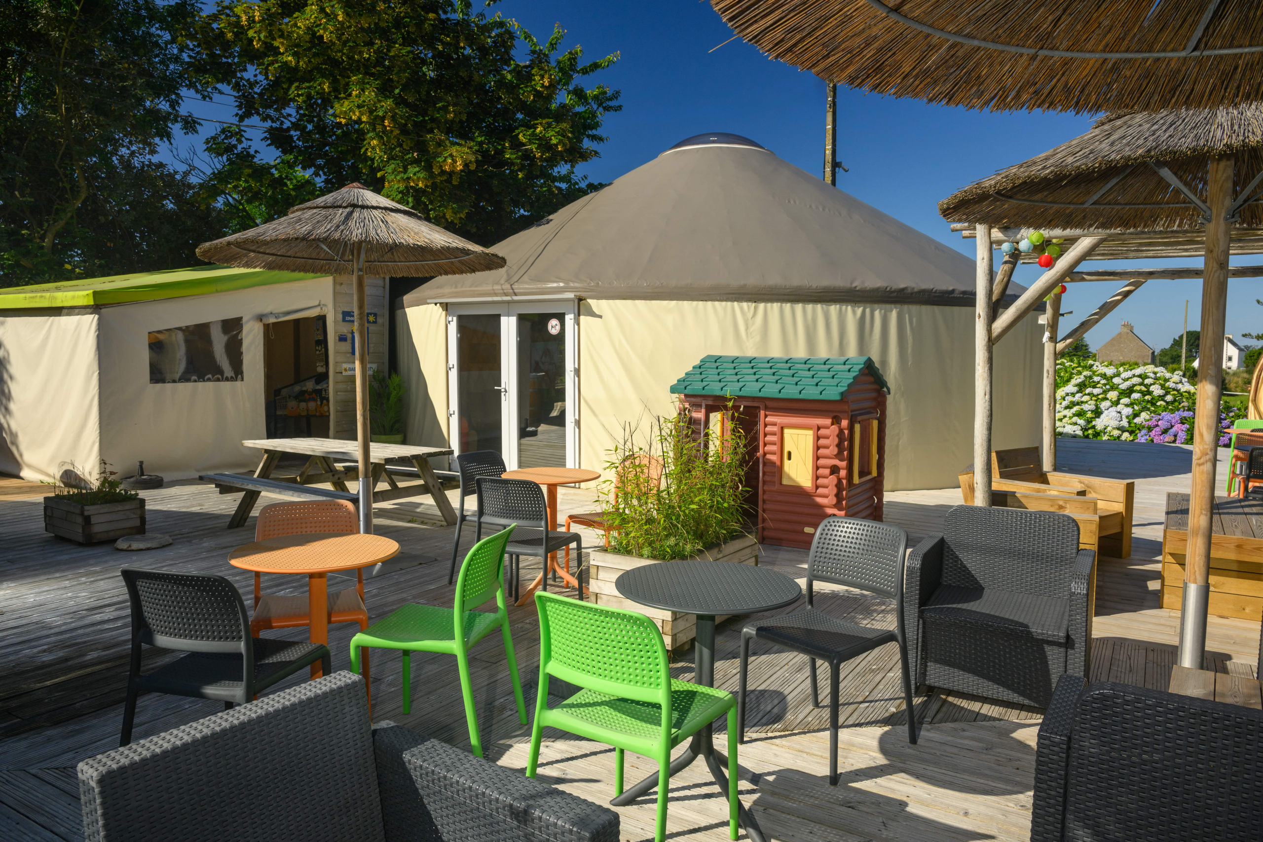 Terrasse extérieure avec tables et chaises colorées.