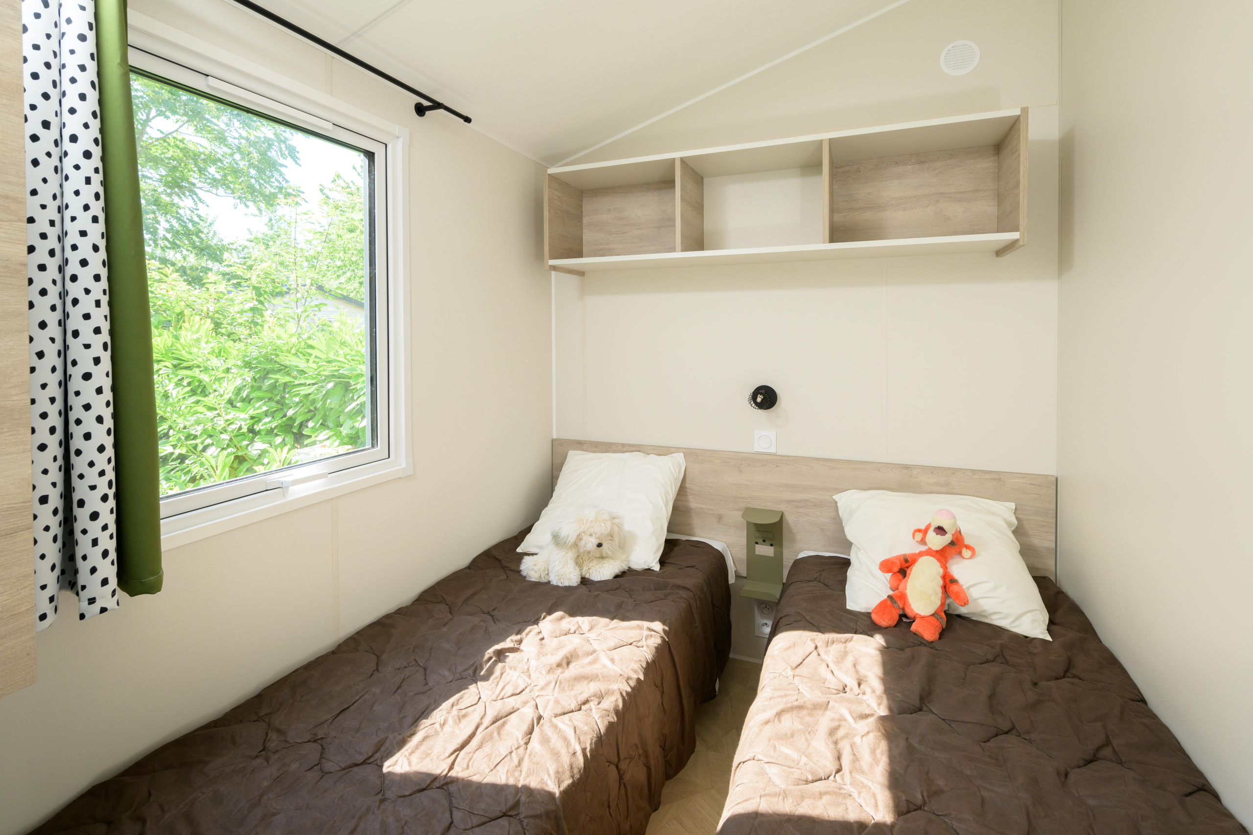 Chambre moderne avec deux lits simples et peluches.