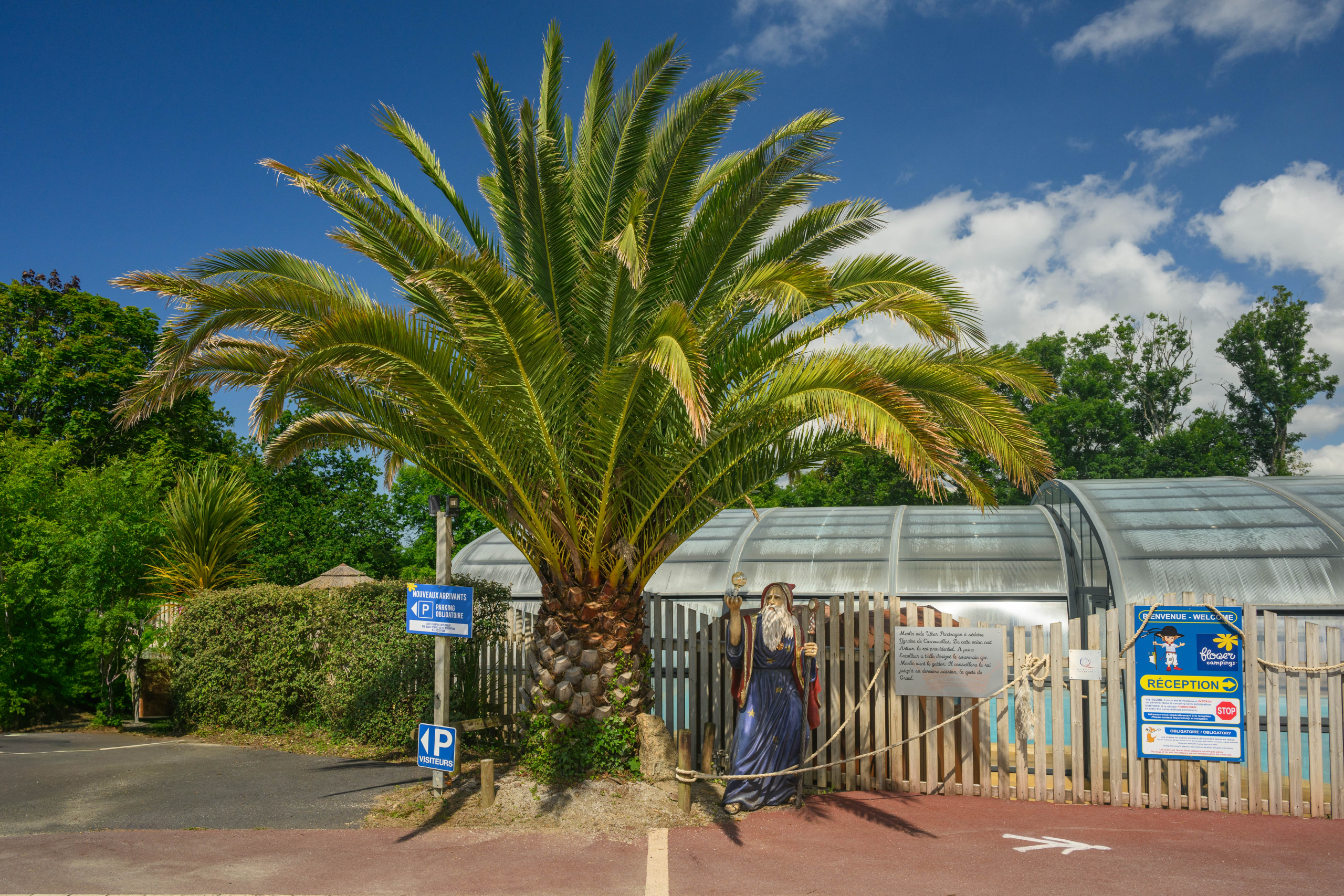 Entrée du parc aquatique avec statue et palmiers.