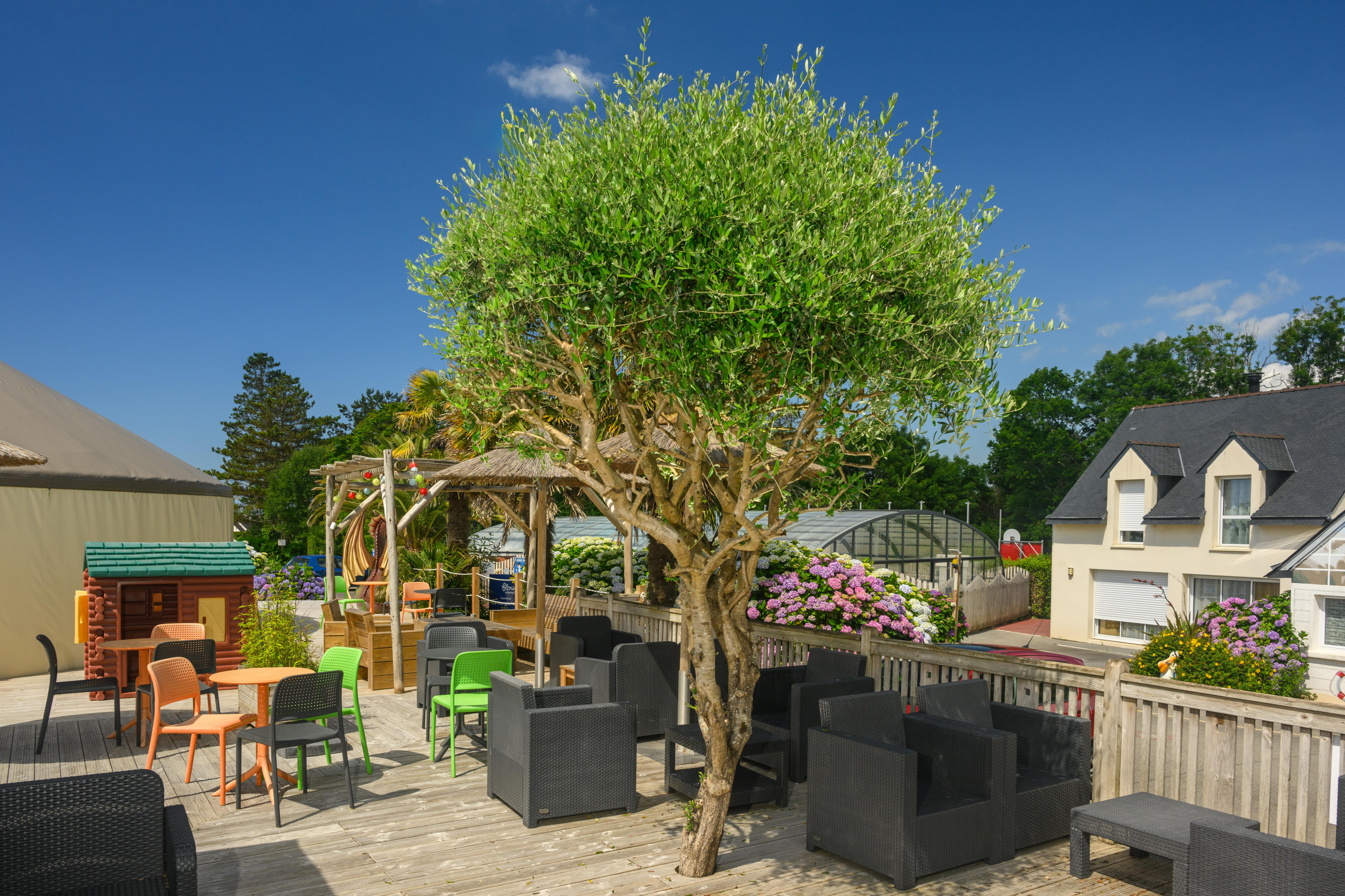 Jardin terrasse avec mobilier coloré et maison.