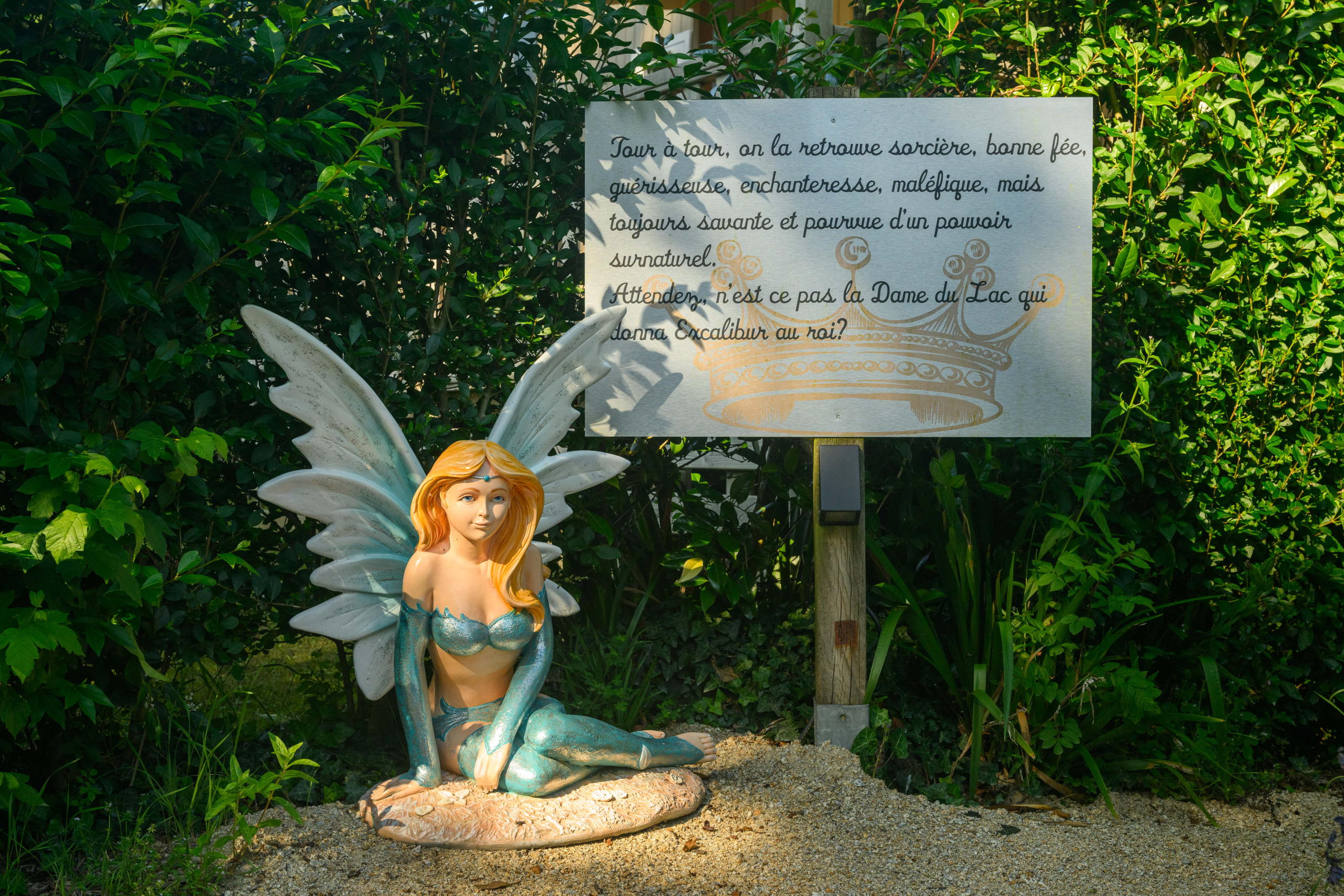 Statue de fée devant un panneau explicatif.