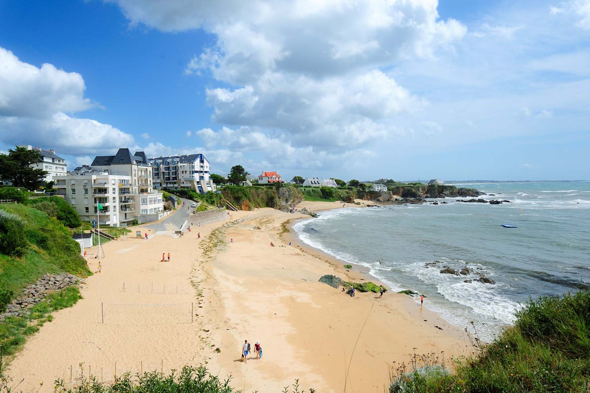 Plage ensoleillée avec bâtiments en bord de mer.