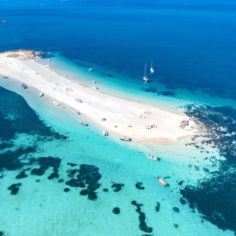 Petite île avec plages et bateaux dans l'océan.