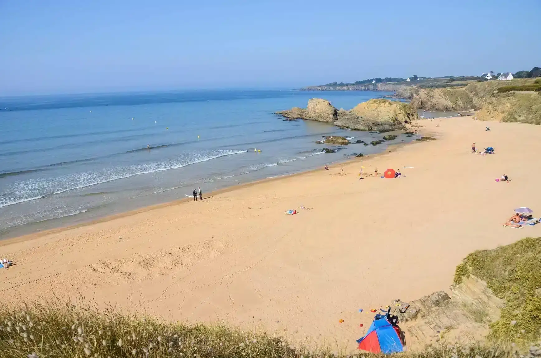 Plage ensoleillée avec sable doré et mer calme.