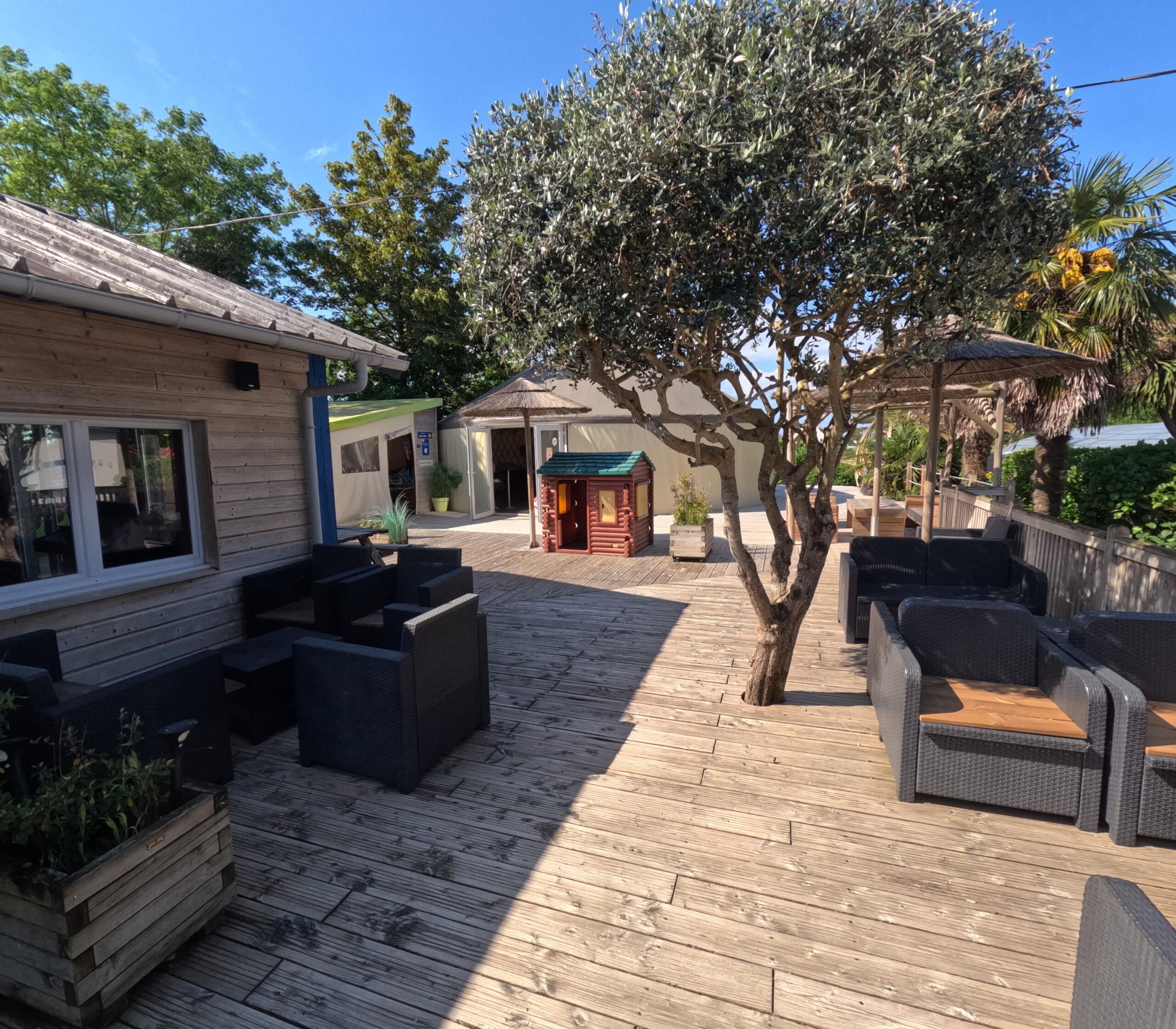 Terrasse en bois avec mobilier et arbres.