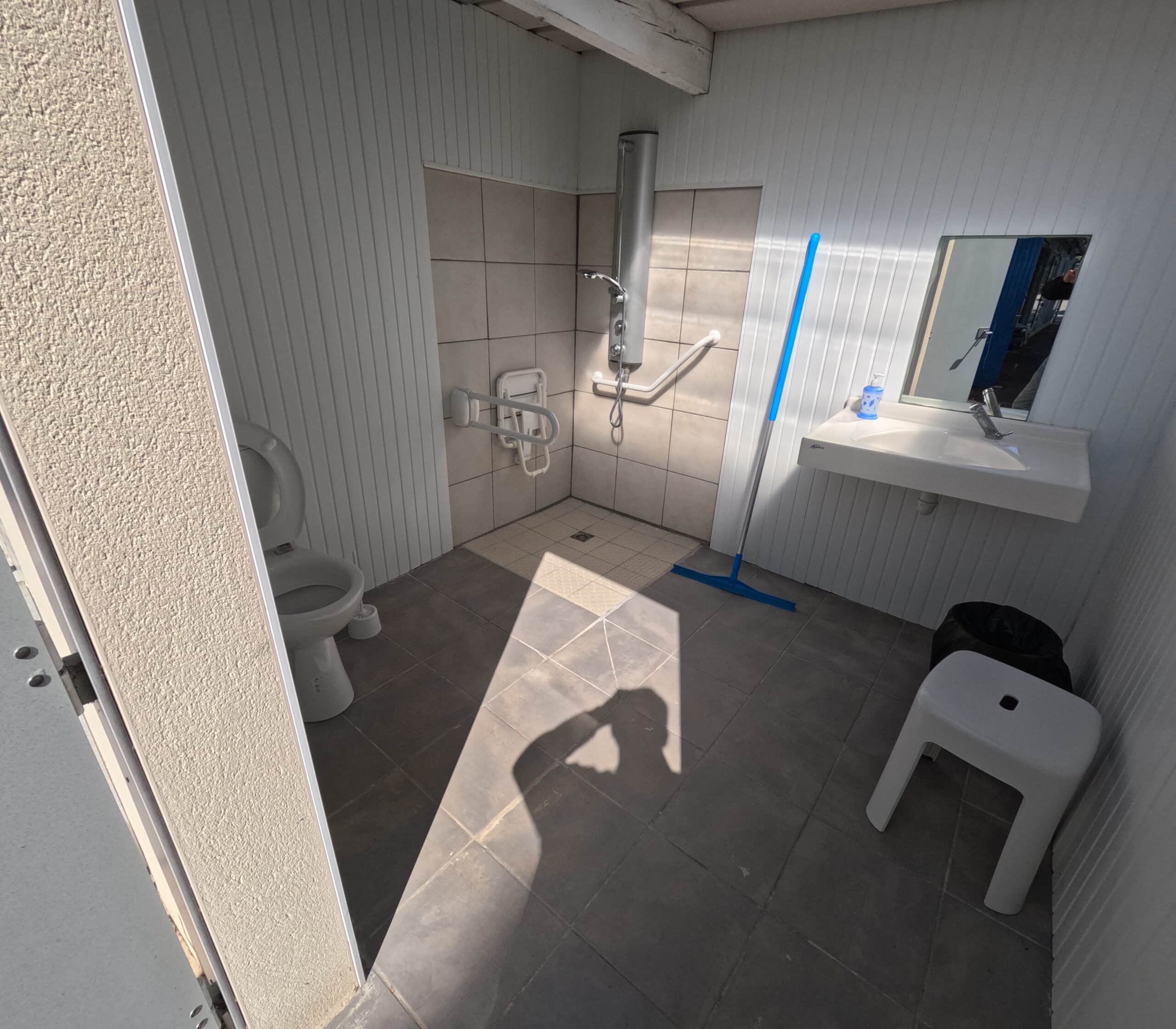 Toilettes accessibles avec douche et lavabo.